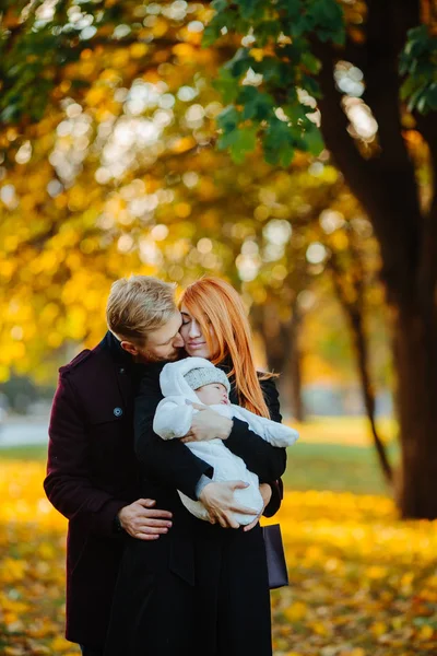 Familia joven e hijo recién nacido en el parque de otoño —  Fotos de Stock