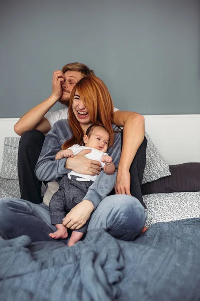 Familia feliz con bebé recién nacido en la cama —  Fotos de Stock