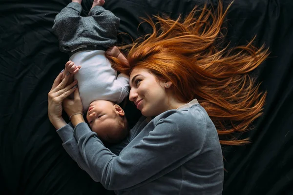 Szczęśliwa matka z dzieckiem razem leżąc na łóżku — Zdjęcie stockowe