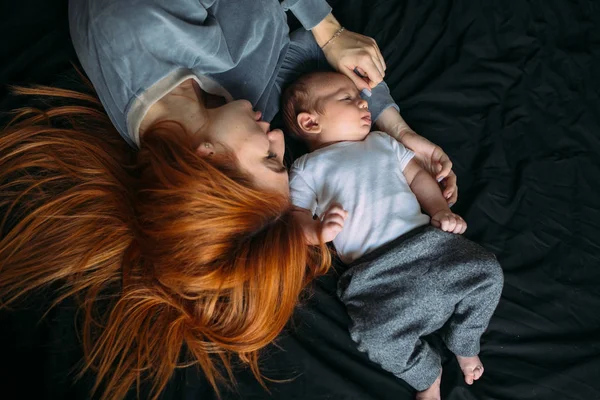 Madre feliz con el bebé acostado juntos en la cama — Foto de Stock