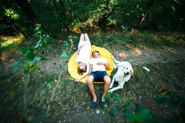 Беременная женщина с мужем, лежащим в парке — стоковое фото