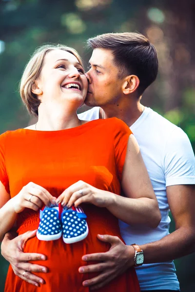 Mulher grávida e seu marido segurando sapatos de bebê — Fotografia de Stock