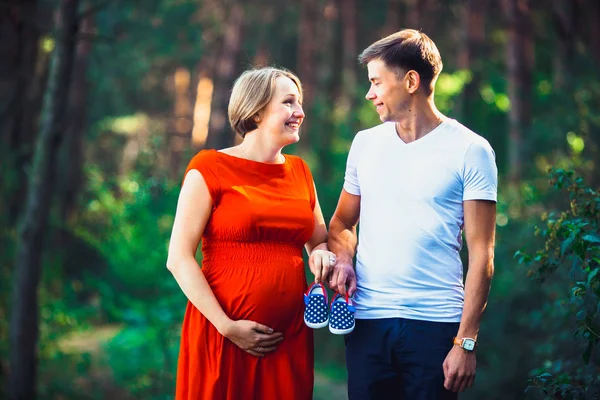 Gravida fru och hennes make håller Babyskor — Stockfoto