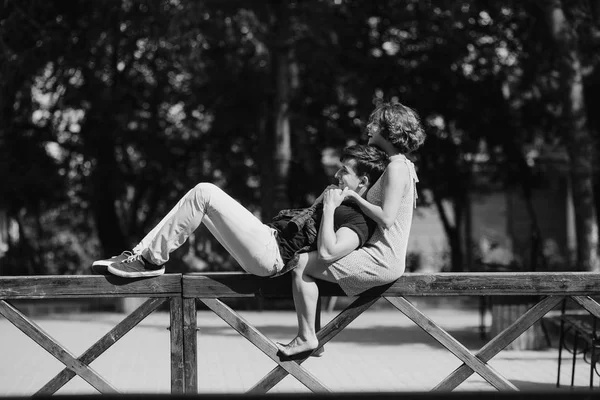 Beautiful young couple resting on a fence — Stock Photo, Image