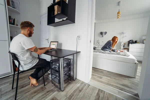 Papa arbeitet am Laptop, Mama und Baby auf dem Bett — Stockfoto