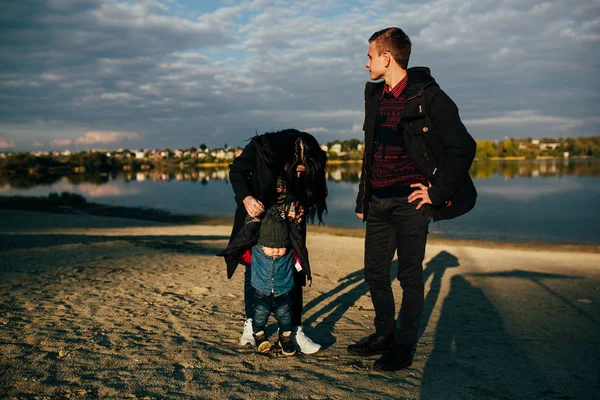 Giovane famiglia e figlio passeggiata lungo la riva del lago — Foto Stock