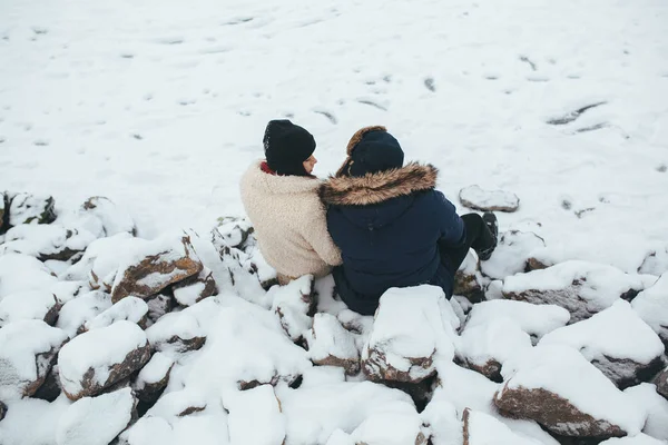 Uomo e donna seduti sulle rocce innevate — Foto Stock