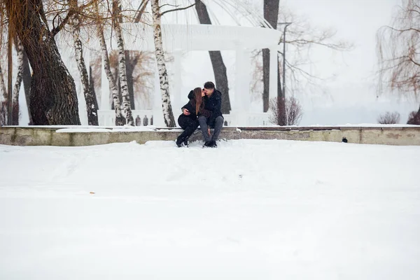Άνδρας και γυναίκα φιλιούνται στο χιονισμένο πάρκο — Φωτογραφία Αρχείου