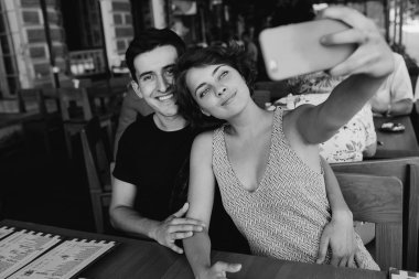 Erkek ve kız dışarıdaki kafede selfie çekiyorlar.