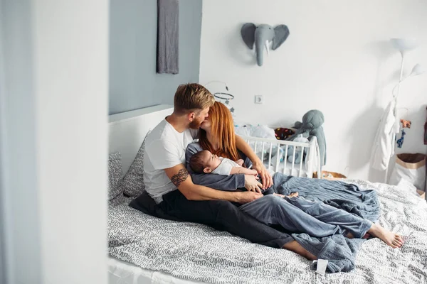 Ευτυχισμένη οικογένεια με το νεογέννητο μωρό στο κρεβάτι — Φωτογραφία Αρχείου