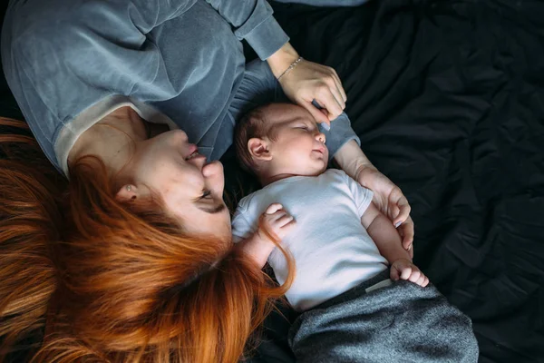 Mutlu anne bebekle birlikte yatakta yatarken — Stok fotoğraf