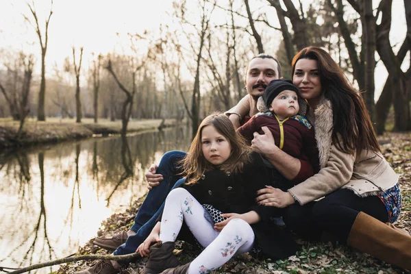 family resting on the river bank