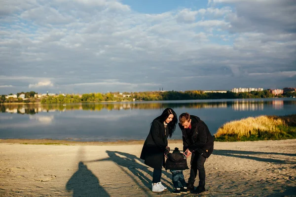 Jovem família e filho caminham ao longo da costa do lago — Fotografia de Stock