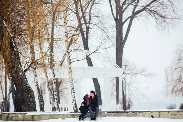 Άνδρας και γυναίκα φιλιούνται στο χιονισμένο πάρκο — Φωτογραφία Αρχείου