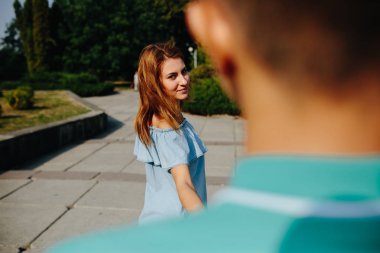 Genç bir kadın parkta sevgilisine yol gösteriyor.