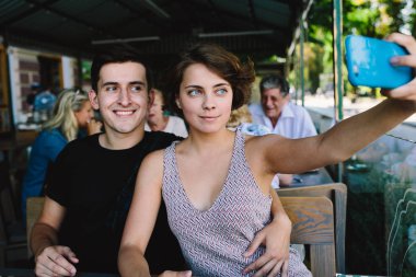 Erkek ve kız dışarıdaki kafede selfie çekiyorlar.