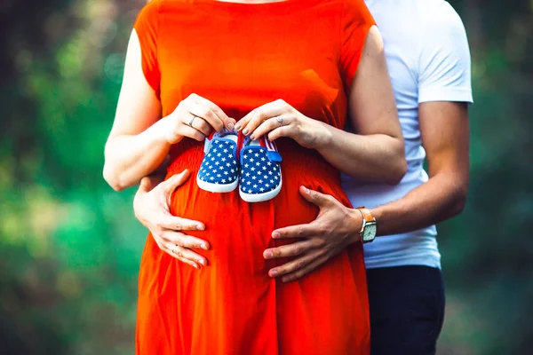 妊娠中の妻と彼女の夫は、赤ちゃんの靴を保持 — ストック写真