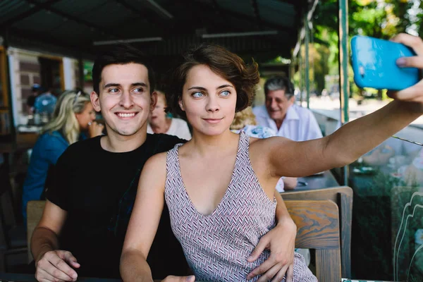 Erkek ve kız dışarıdaki kafede selfie çekiyorlar.