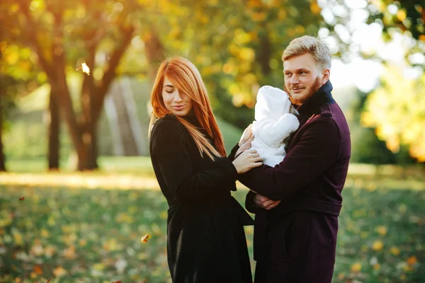 Familia joven e hijo recién nacido en el parque de otoño —  Fotos de Stock