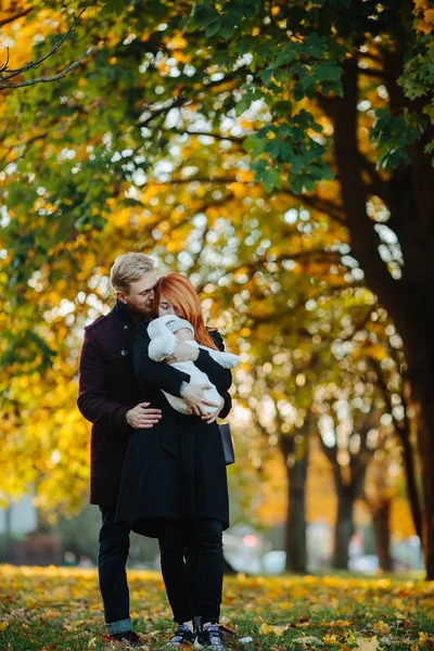 Familia joven e hijo recién nacido en el parque de otoño —  Fotos de Stock