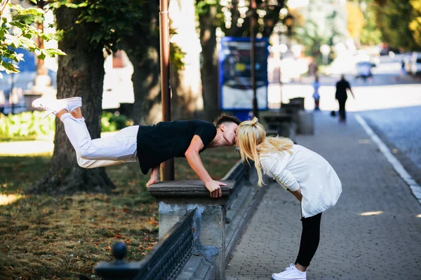 Uomo esegue un trucco acrobatico vicino a una ragazza — Foto Stock