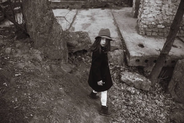 Liten flicka i en svart kappa och hatt — Stockfoto