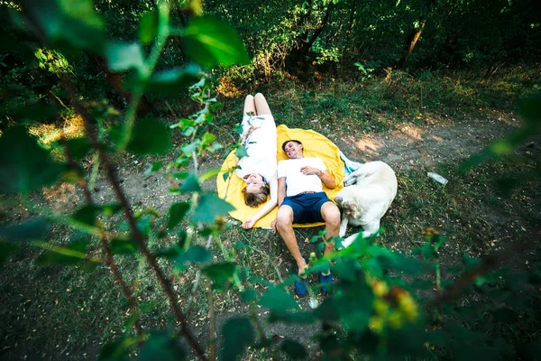 Беременная женщина с мужем, лежащим в парке — стоковое фото
