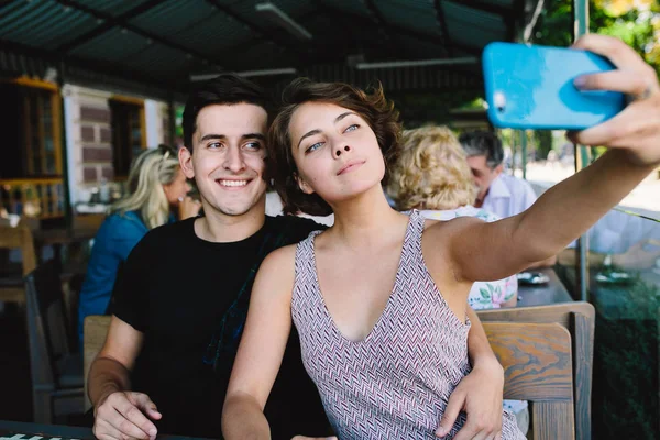 Erkek ve kız dışarıdaki kafede selfie çekiyorlar.