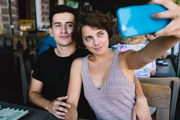 Erkek ve kız dışarıdaki kafede selfie çekiyorlar.