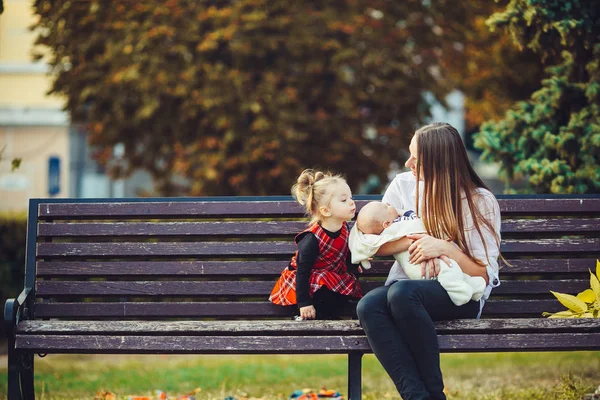 Mor och två döttrar vilar på en bänk — Stockfoto