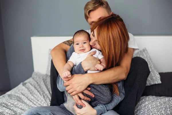 Šťastná rodina s novorozené dítě na posteli — Stock fotografie