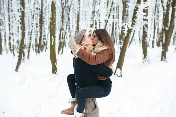Gars tient la fille sur les mains dans le parc à neige — Photo