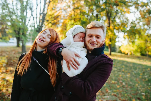 Молодая семья и новорожденный сын в осеннем парке — стоковое фото