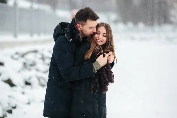 Par poserar i en snöig park — Stockfoto