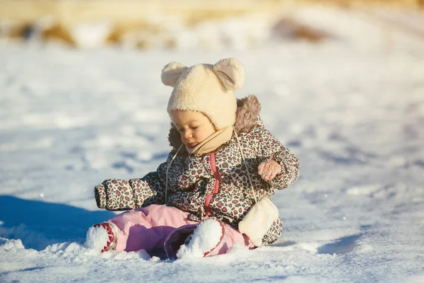 Μικρό κορίτσι που κάθεται στο χιόνι — Φωτογραφία Αρχείου