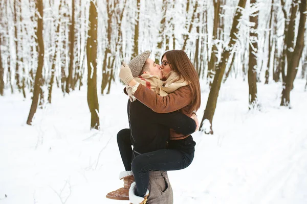 Chico sostiene a la chica en las manos en el parque de nieve — Foto de Stock