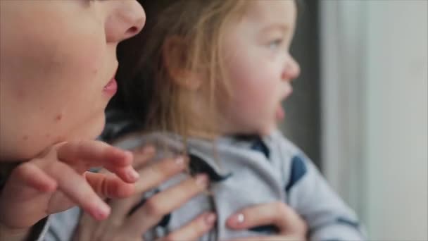 Mamá con niña mirando por la ventana — Vídeo de stock