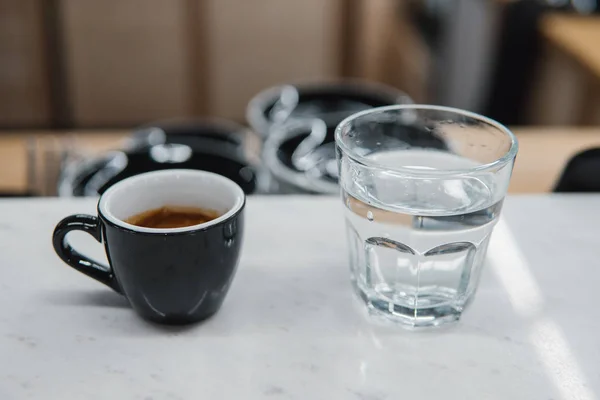 Cup with coffee near a glass of water — Stock Photo, Image