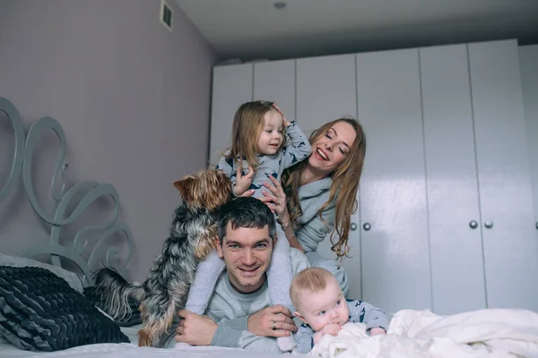 Famiglia che gioca sul letto in camera da letto — Foto Stock