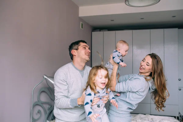 Familia jugando en la cama en el dormitorio — Foto de Stock