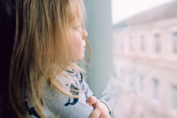 Niña de pie cerca de la ventana y mirando — Foto de Stock