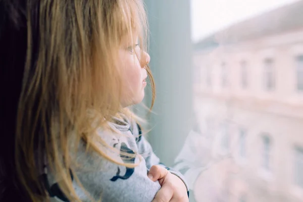 Little girl standing near window and looking Royalty Free Stock Photos