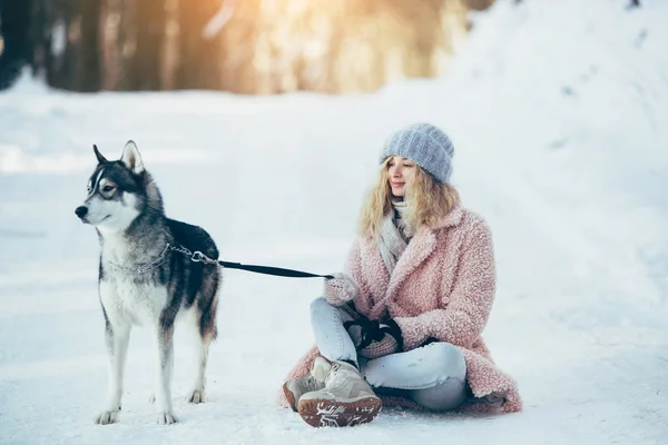 Vacker flicka med hund Husky i snöiga skogen — Stockfoto