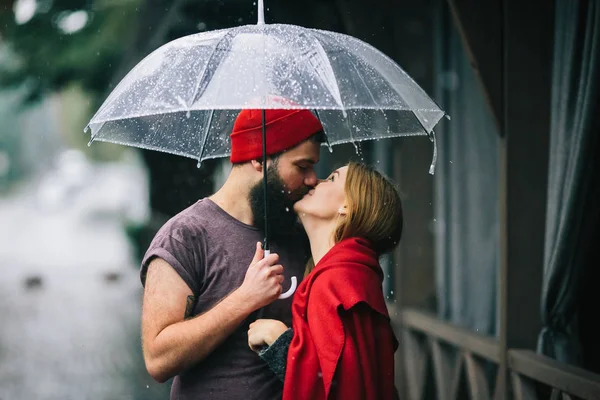 Парень и девушка целуются под зонтиком — стоковое фото