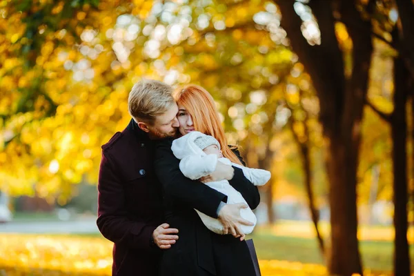 Familia joven e hijo recién nacido en el parque de otoño —  Fotos de Stock