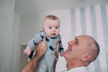 Büyükbaba torunu elinde tutuyor.