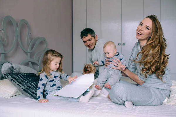 Familia jugando en la cama en el dormitorio — Foto de Stock