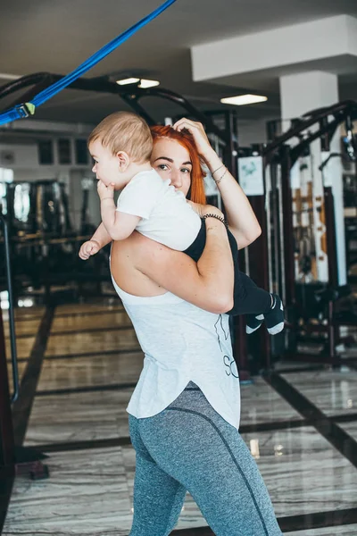 Joven madre con su hijo pequeño en el gimnasio — Foto de Stock