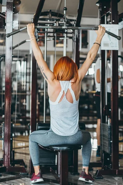 Woman training her back and shoulder with in a gym