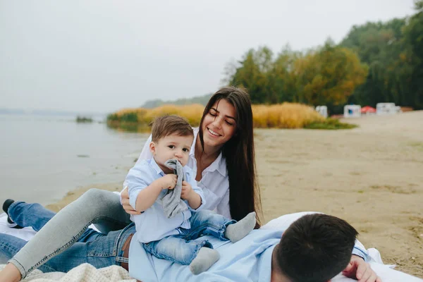 Szczęśliwa młoda rodzina relaksująca się razem nad jeziorem — Zdjęcie stockowe